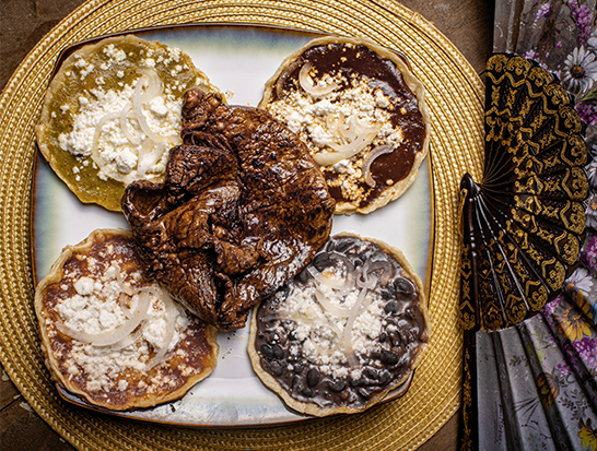 Delicious Quesabirrias - crispy tortillas filled with tender birria meat, served with rich consommé and fresh lime